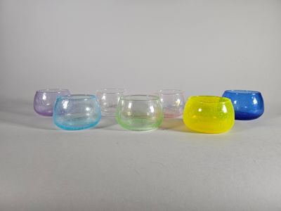 six bols en verre de couleurs différentes alignés les uns à côté des autres sur une surface blanche