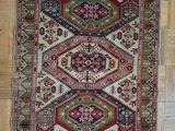 a red and green rug on a wooden floor next to a chair
