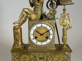 une horloge en or avec une femme assise dessus