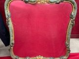 une photo d'une chaise rouge sur laquelle repose un cadre doré