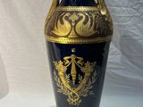un vase bleu orné de motifs dorés sur fond blanc