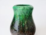 a green vase that is sitting on a white surface