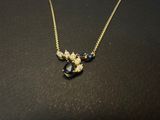 a close up of a necklace on a table with a black and gold necklace