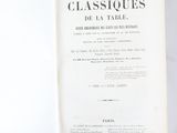 an open book sitting on top of a table next to a white tablecloth