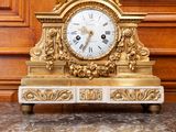 a gold clock sitting on top of a marble table