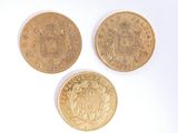 three gold coins sitting on top of each other on a white surface