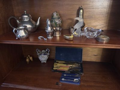 une étagère en bois sur laquelle sont posés une théière, un pot à thé et d'autres objets