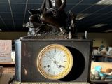 une statue représentant une femme assise sur une horloge posée sur une table