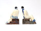 two figurines of a man and woman sitting next to each other