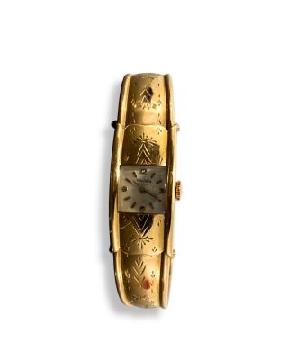 une montre en or posée sur une surface blanche