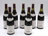 six bottles of wine are lined up in a row on a white surface