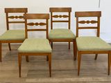 quatre chaises en bois, dont les assises sont recouvertes de tissu vert, sont posées sur un parquet