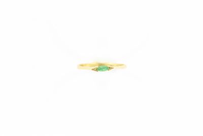 gros plan d'une bague en or avec une pierre verte