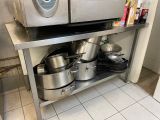 pots and pans are stacked on a stainless steel shelf in a kitchen