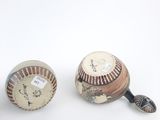 two baseballs sitting next to each other on a white surface