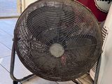 un ventilateur posé par terre à côté d'un réfrigérateur