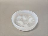 a bowl of water with ice in it on a table