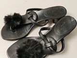 pair of black leather sandals with fur pom poms on them