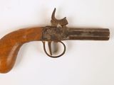 un vieux pistolet avec une poignée en bois sur une surface blanche