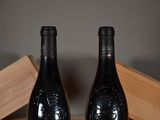 two bottles of wine sitting on a table next to each other