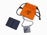 an orange bag with a silver pendant and a black wallet
