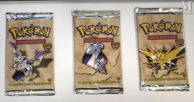 three packs of pokemon trading cards sitting on top of a counter