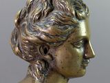 bronze bust of a woman with curly hair on a gray background