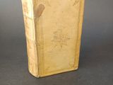 an old book sitting on top of a table next to a gray wall