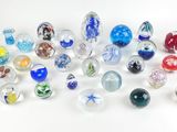 de nombreuses billes de verre de différentes couleurs sur une surface blanche