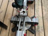 une scie circulaire posée sur une terrasse en bois, à côté d'une boîte à outils