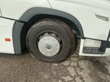 un bus blanc avec un pneu crevé, garé sur un parking