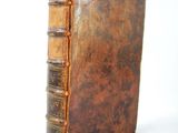 an old book sitting on top of a white table next to a white wall