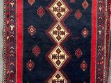un tapis bleu et rouge accroché au mur, à côté d'un mur