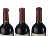 four bottles of wine are lined up in a row on a white surface