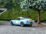 a blue car parked in a parking lot next to a tree