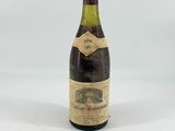 an old bottle of wine sitting on top of a white table