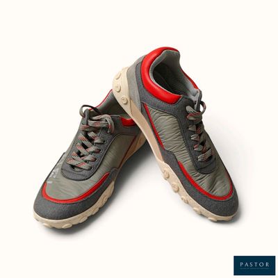 une paire de baskets grises et rouges posées sur une surface blanche, avec un fond blanc