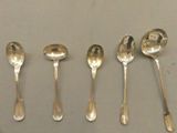 six cuillères en argent sont alignées les unes à côté des autres sur une table