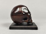 an image of a small bronze skull on a wooden base