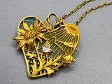 a close up of a gold necklace with a heart and flowers on it