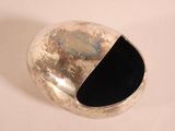 a silver object with a black center on a white surface