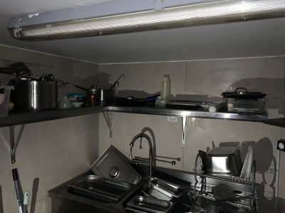 une cuisine équipée d'un évier, d'une cuisinière et d'autres éléments posés sur le plan de travail