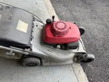 a lawn mower that is sitting on the sidewalk