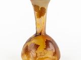 a glass vase with leaves on it on a white surface