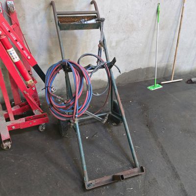 a red hand truck with a hose attached to the back of it