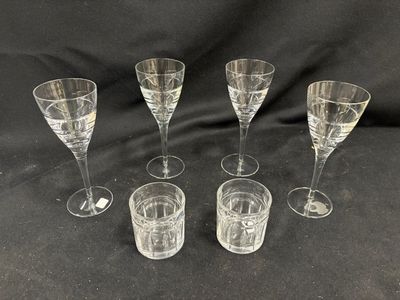 six verres à vin transparents posés les uns à côté des autres sur un fond noir