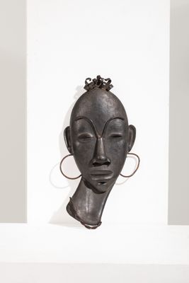 un gros plan sur une sculpture représentant le visage d'une femme, posée sur une étagère