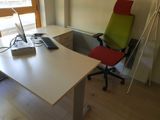 a desk with a computer and a chair in front of a window