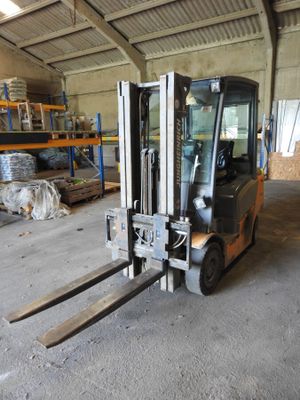 a forklift in a warehouse with pallets in the background