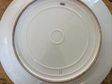 a white plate with a gold rim sitting on a table